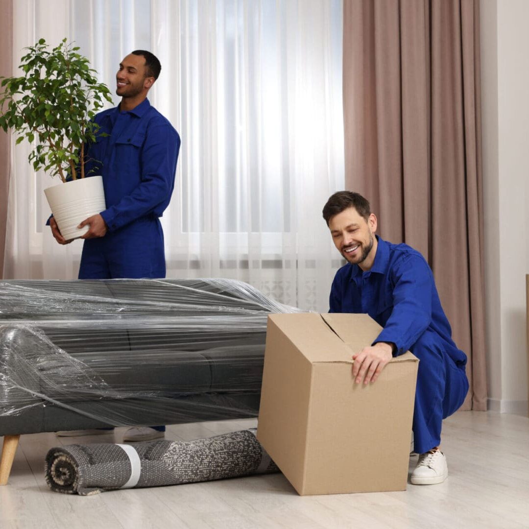 Men moving furniture and boxes in apartment.